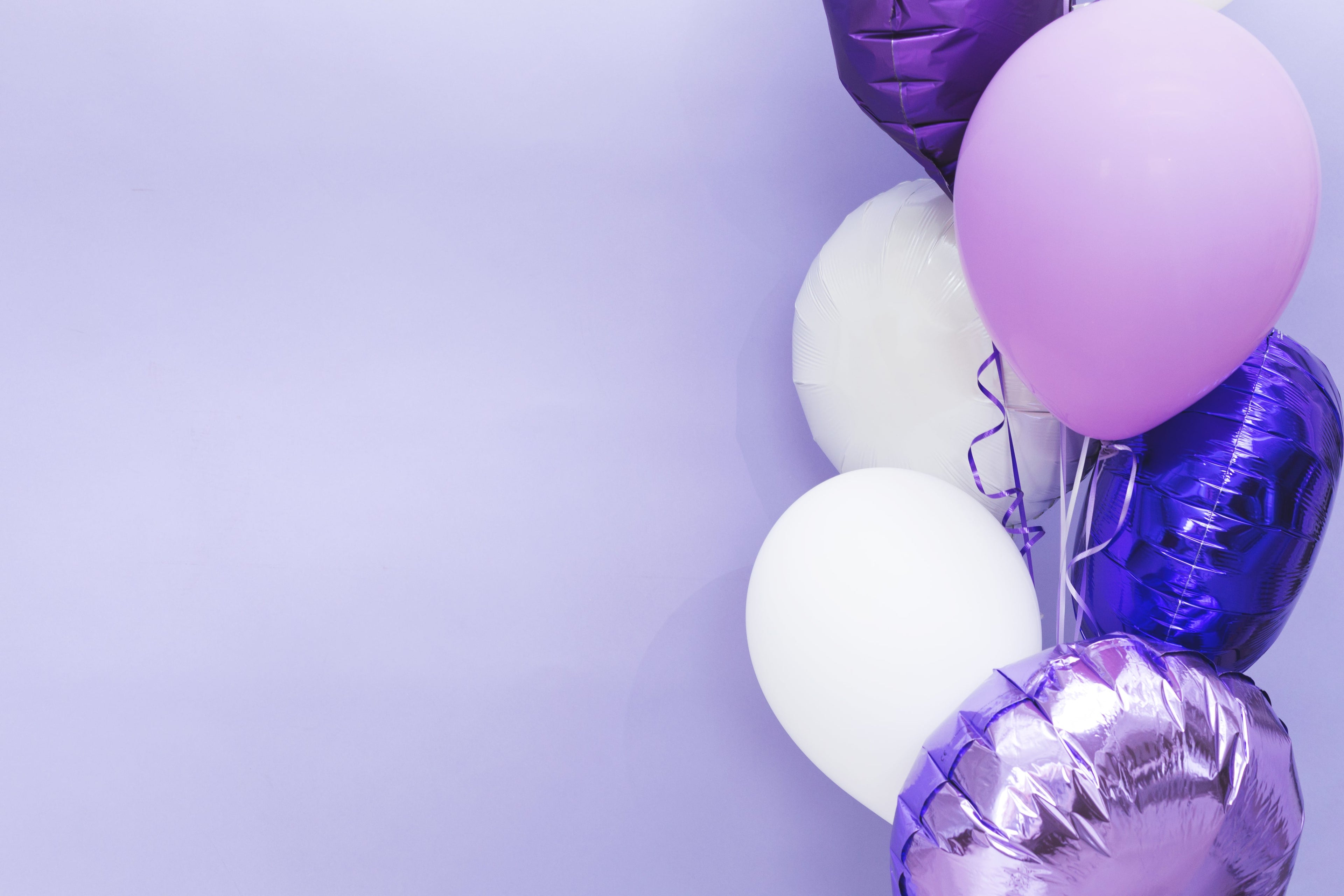 Purple, white, and blue balloons on a light purple background