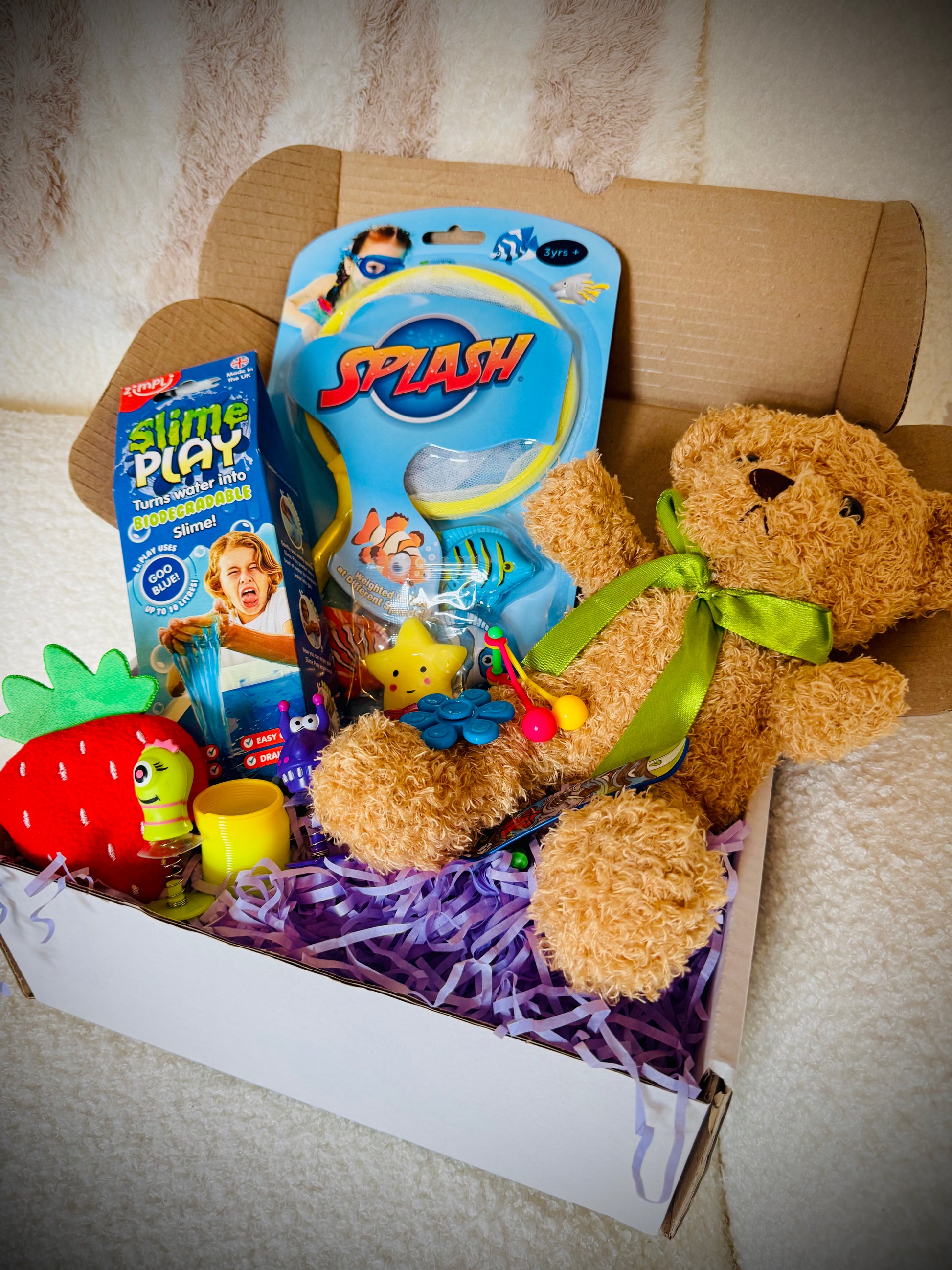 A selection of kids toys in a gift box with a handwritten card £20