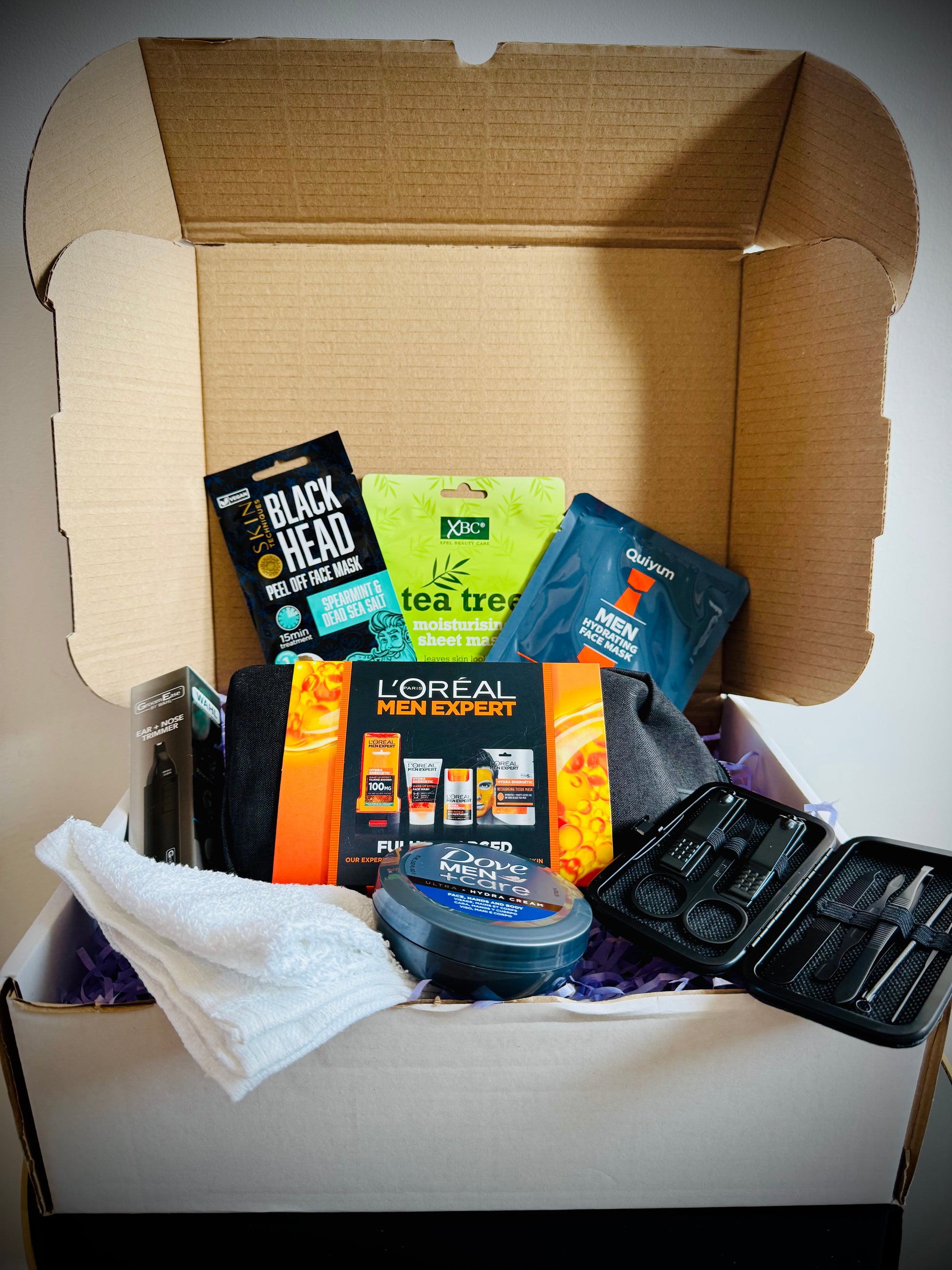 Collection of men's grooming products including face masks, soap, and lotion in a gift box with a handwritten card £50