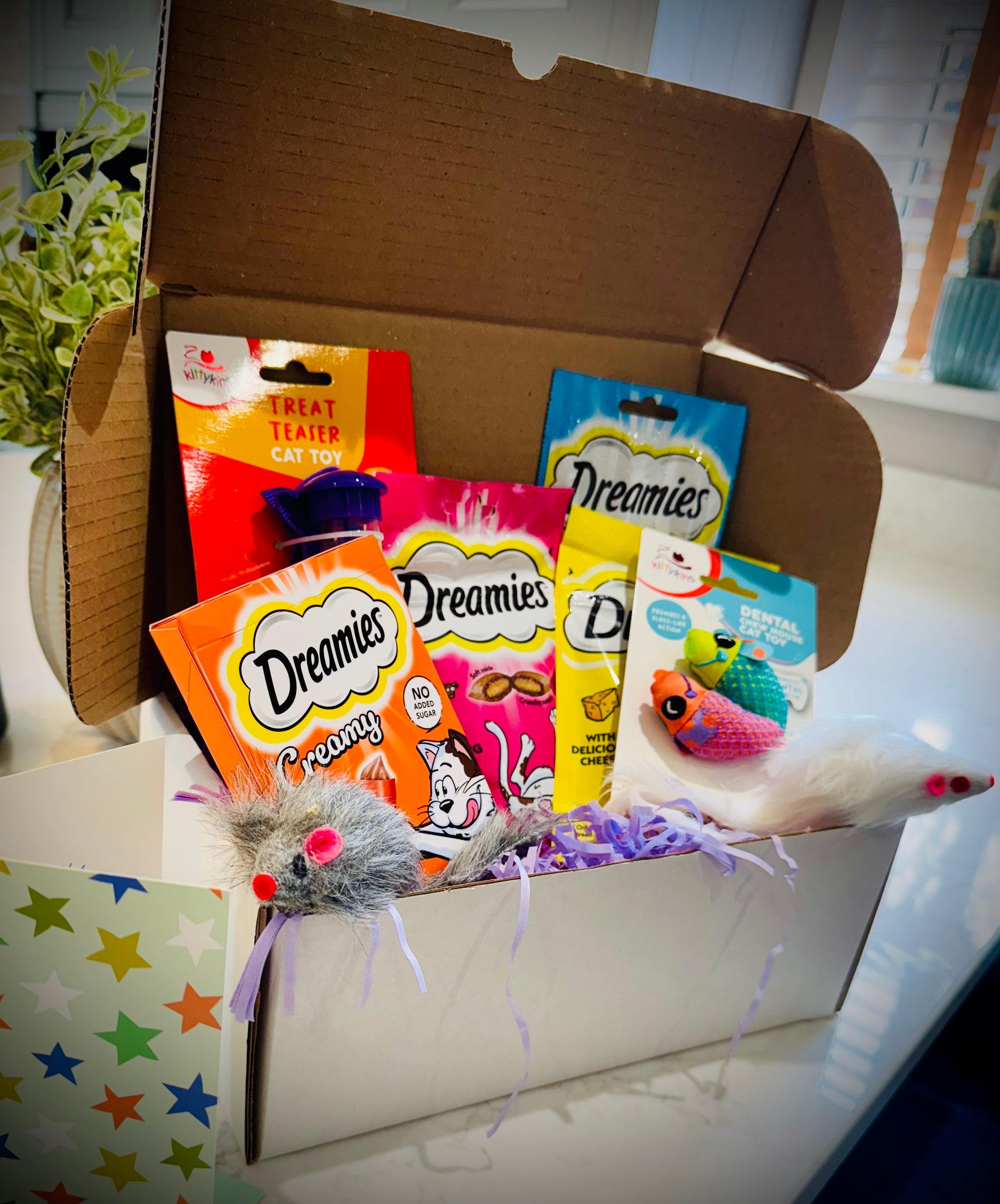 Assorted cat treats and toys with Dreamies packaging in a gift box with a handwritten card £20